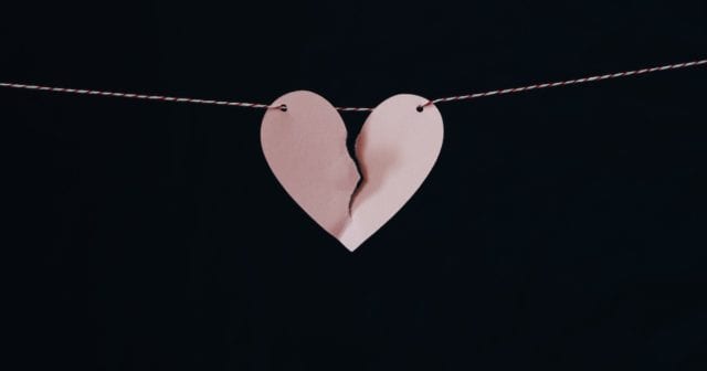 a pink paper heart ripped in half representing the difficulties of dealing with a divorce and the associated insurance changes