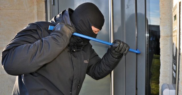 a burglar breaking ijnto a home while the family is on vacation