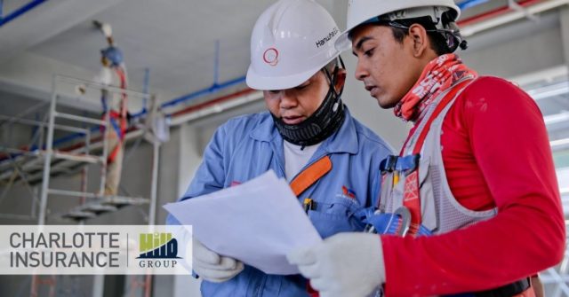 two construction workers holding a paper and discussing ways to lower their workers' compensation insurance experience mod.