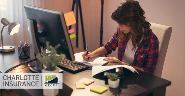 a woman sitting at a desk at her computer researching insurance options for her home based business