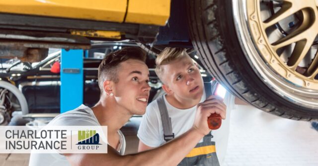 2 mechanics working under a car while discussing the importance ot a modified car insurance policy